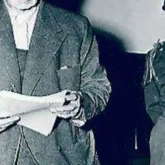 Ein Mann im Anzug hält Dokumente, daneben ein Soldat. Möglicherweise im Zusammenhang mit dem Flick-Konzern.