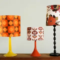 Tres pantallas de lámpara de pie, una de 40 cm, con estampados retro: geométrico naranja, flores marrones y un diseño floral vibrante.