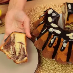 Najbardziej wilgotna babka marmurkowa z polewą czekoladową i płatkami migdałów. Kawałek ciasta na talerzyku.