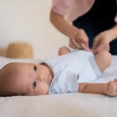 Malutkie dziecko leży na białym tle. Mama przygotowuje się do szczepienia RSV w ciąży, dbając o bezpieczeństwo maluszka.