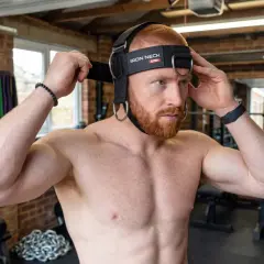 Man adjusting a neck training harness, ready for a workout. This image captures the start of his neck training journey.