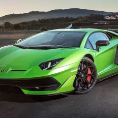Jaskrawozielony Lamborghini Aventador SV na torze wyścigowym, z górami w tle.