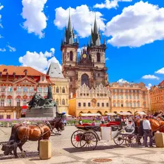 Rynek w Pradze z kościołami, kamienicami i dorożkami konnymi.