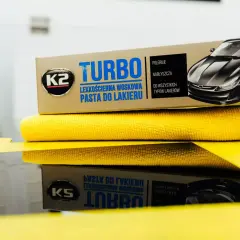 K2 Turbo pasta do lakieru samochodowego na żółtej mikrofibrze, gotowa do polerowania.