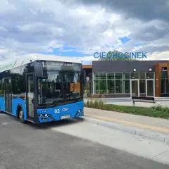 Niebieski autobus ekologiczny z napisem "Ciechocinek Dworzec" czeka na pasażerów. W tle nowoczesny budynek dworca z napisem "Ciechocinek".