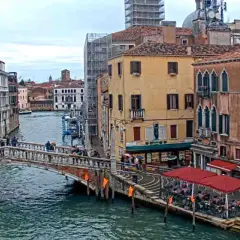 Il ponte delle Guglie attraversa un canale veneziano, circondato da edifici storici e persone che passeggiano.