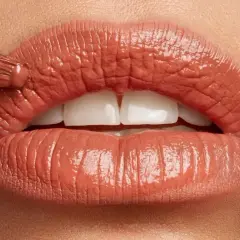 Labbra perfette con un tocco di colore. Un pennello applica un prodotto cremoso, mentre un rossetto definisce il contorno.