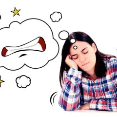 Mujer dormida con un globo de pensamiento que muestra una boca enfadada, como si soñara que se le cae una muela.