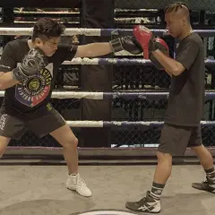 A boxer throws a jab punch during training in a boxing ring.