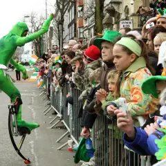 Zielony ludek na szczudłach podczas parady. Gdzie kupić piwo irlandzkie zielone? Może na festynie!