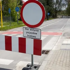 Znak B1 zakazu ruchu z tabliczką "Nie dotyczy pojazdów budowy" na tle drogi z pasami.