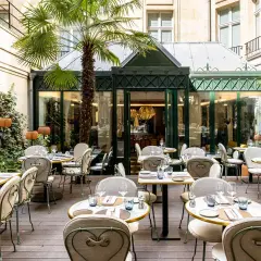 Cour intérieure d'un restaurant chic, tables dressées sous un palmier, ambiance paisible, comme un blossom de sérénité.
