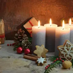 Vier Kerzen, Geschenke und Tannenzweige erzählen die Geschichte von Weihnachten. Lebkuchen und Zimtstangen runden die festliche Szene ab.