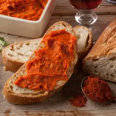 Nduja co to? Pikantna, smarowna kiełbasa na chlebie, obok przyprawy i ziół. Idealna na przekąskę.