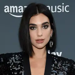 Mujer con un elegante corte pelo bob oscuro, maquillaje dramático y un blazer de lentejuelas.
