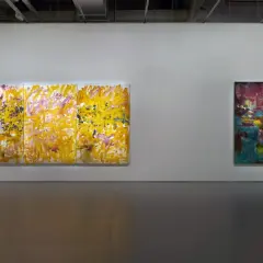 Abstract paintings by Megan Rooney displayed in a gallery. One is a triptych of vibrant yellow and pink strokes, the other a dark, moody canvas.