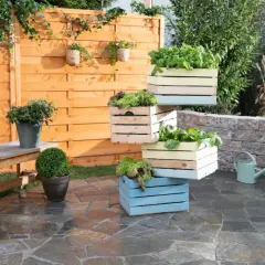 Fioriera fai da te con cassette di legno colorate, piene di verdure fresche, su un patio in pietra.