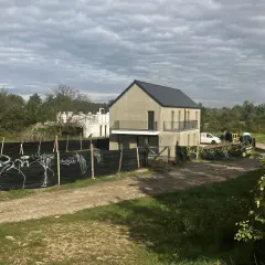 Plac budowy z niedokończonymi domami, ogrodzony czarną siatką z graffiti. Może to symbolizować zakaz budowy domów jednorodzinnych w tej okolicy.