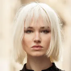 Mujer joven con un moderno corte bob rubio platino y maquillaje sutil.