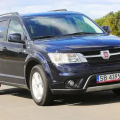 Ciemnoniebieski Fiat Freemont w ruchu drogowym. Wiele osób szuka o nim opinii, bo to praktyczny SUV.