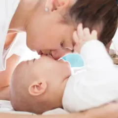 Ciepły uścisk mamy i jej 2 miesięczne dziecko. Delikatne pocałunki i miłość w spojrzeniu.