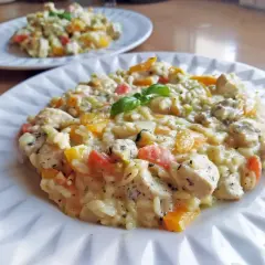 Szybkie risotto z kurczakiem i kolorowymi warzywami, ozdobione listkiem bazylii. Idealne na szybki obiad.