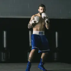 A boxer, ready to fight, demonstrates his switch hitter stance in a boxing gym.