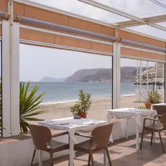 Mesas listas para cenar en el asador La Chumbera, con vistas al mar y la playa.