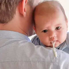 Neonato allattato al seno con reflusso, rigurgita latte sul pigiama del papà.