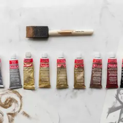 A collection of Rub'n Buff wax metallic finish tubes in various colors, alongside a foam applicator brush, ready to add a beautiful sheen to any project.