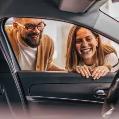 Ett leende par tittar in i en ny bil. De funderar på hur funkar privatleasing för att få sin drömbil.