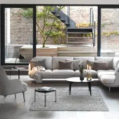 Modernes wohnzimmer mit 2 Sofas, einem Sessel und großem Fenster zum Garten mit Treppe.
