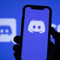 Dłoń trzyma smartfon z logo Discord. Aplikacja ta służy do komunikacji, więc jeśli zastanawiasz się "discord co to", to właśnie ją widzisz.