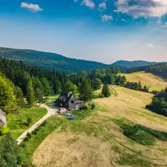 Malownicza bacówka nad Wierchomlą, gdzie trasa turystyczna prowadzi przez zielone wzgórza i lasy.