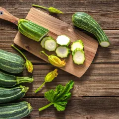 Frische Zucchini, einige roh geschnitten, liegen auf einem Holzbrett. Perfekt, um Zucchini roh zu essen!