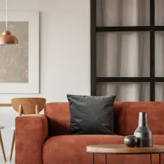 Gemütliche Wohnung inspo: Orange Couch, Holztisch mit Stühlen und ein kupferfarbener Lampenschirm.