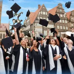 Absolventen der Apollon Hochschule werfen ihre Hüte in die Luft. Tolle Erfahrungen und ein erfolgreicher Abschluss!