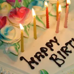 Pastel de cumpleaños con rosas de crema y velas encendidas. ¡Espero que estos textos de cumpleaños para mi novio largas hagan llorar de emoción!