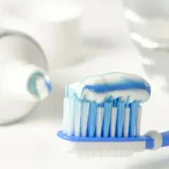 Szczoteczka z biało-niebieską pastą, zawierającą monofluorofosforan sodu, gotowa do mycia zębów.