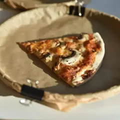 Kawałek pizzy z pieczarkami na papierowym talerzu. Zastanawiasz się nad ciasto na pizze kcal?