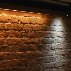Ciepłe oświetlenie ściany z cegły ledami tworzy przytulną atmosferę.
