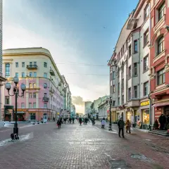 Zimowy spacer po Arbat w Moskwie. Ludzie przechadzają się brukowaną ulicą między kolorowymi kamienicami, a w oknach sklepów migoczą świąteczne dekoracje.