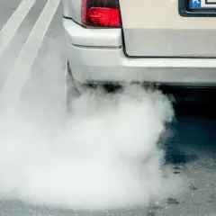 Z rury wydechowej samochodu wydobywa się gęsty, biały dym, który przypomina parę wodną.