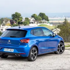 Un Seat Ibiza 1.2 gasolina, azul brillante, aparcado en un paisaje con casas y árboles. Opiniones sobre su diseño y rendimiento.