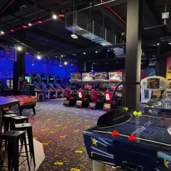 Ambiance de fête foraine à Montparnasse, avec des jeux d'arcade, des tables de air hockey et des murs décorés "Smile world".
