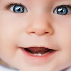 Occhi azzurri e un sorriso che mostra il primo dentino. Una bellissima vista neonati che incanta.