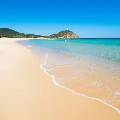 Piękne plaże Cagliari z turkusową wodą i złotym piaskiem. W oddali widać wzgórze z wieżą.