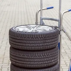 Stos czterech opon na wózku. Zastanawiasz się, ile waży opona? Ten zestaw jest gotowy do transportu.