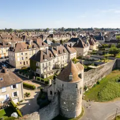 Vue aérienne d'une ville fortifiée de la Suisse Normande, avec ses toits en ardoise, ses maisons en pierre et sa tour médiévale.