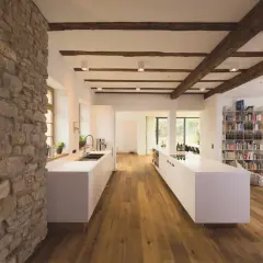 Modernes Wohnen mit Fachwerk: Eine Küche mit weißen Inseln und Holzbalken, die das Fachwerk innen gestalten.